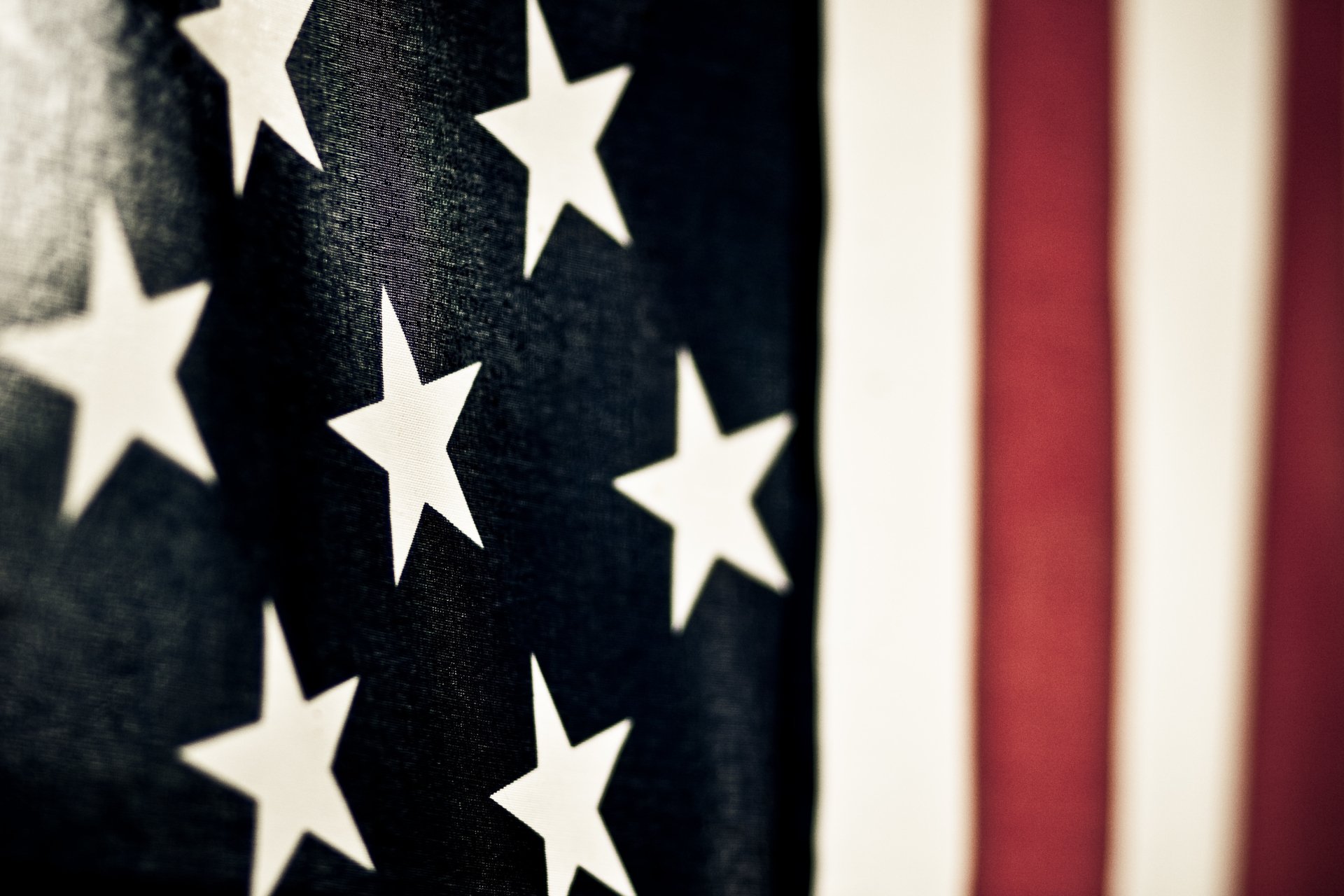 Close-up of an American flag's stars and stripes on man-made fabric, 2K Quad HD PC desktop wallpaper background.