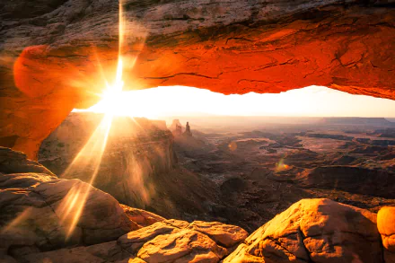 Sunrise illuminates Utah’s Mesa Arch, casting warm light over the vast horizon and rugged landscape in this stunning 4K Ultra HD nature wallpaper.
