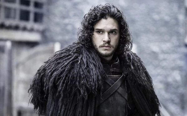 Jon Snow, portrayed by Kit Harington in Game of Thrones, stands in a dramatic pose wearing his signature dark fur cloak, set against a somber background of the show's medieval landscape.