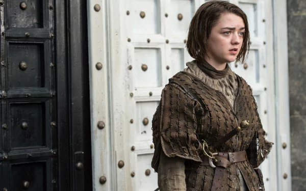 4K Ultra HD wallpaper featuring Maisie Williams as Arya Stark from the TV show Game of Thrones, dressed in medieval armor standing against a large metal door.