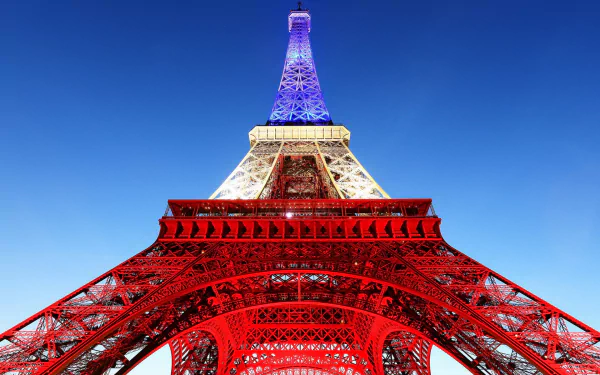 HD desktop wallpaper of the Eiffel Tower in Paris bathed in French flag blue, white and red, shot from below to emphasize the man-made monument.