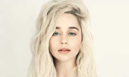 Close-up of Emilia Clarke, an English actress with striking green eyes and blonde hair, presented as a high-definition desktop wallpaper.