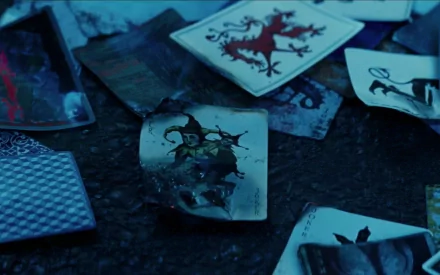 A captivating HD wallpaper featuring playing cards scattered on the ground, showcasing the Joker from Batman Begins, emphasizing the film's dark and chaotic vibe.