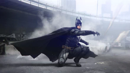 HD PC desktop wallpaper featuring Batman from the movie The Dark Knight Rises, crouched with cape flowing in a smoky urban setting.