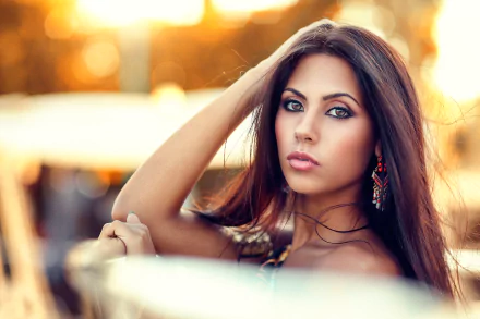Brunette woman with striking brown eyes poses against a warm bokeh background, captured in high-definition for a PC desktop wallpaper.