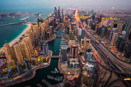 A tilt-shift aerial view of Dubai’s skyscrapers and cityscape along the waterfront, showcasing the vibrant urban skyline of the United Arab Emirates at dusk.