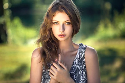A brunette model stands with a serene expression, surrounded by a softly blurred natural background, creating an engaging HD desktop wallpaper.