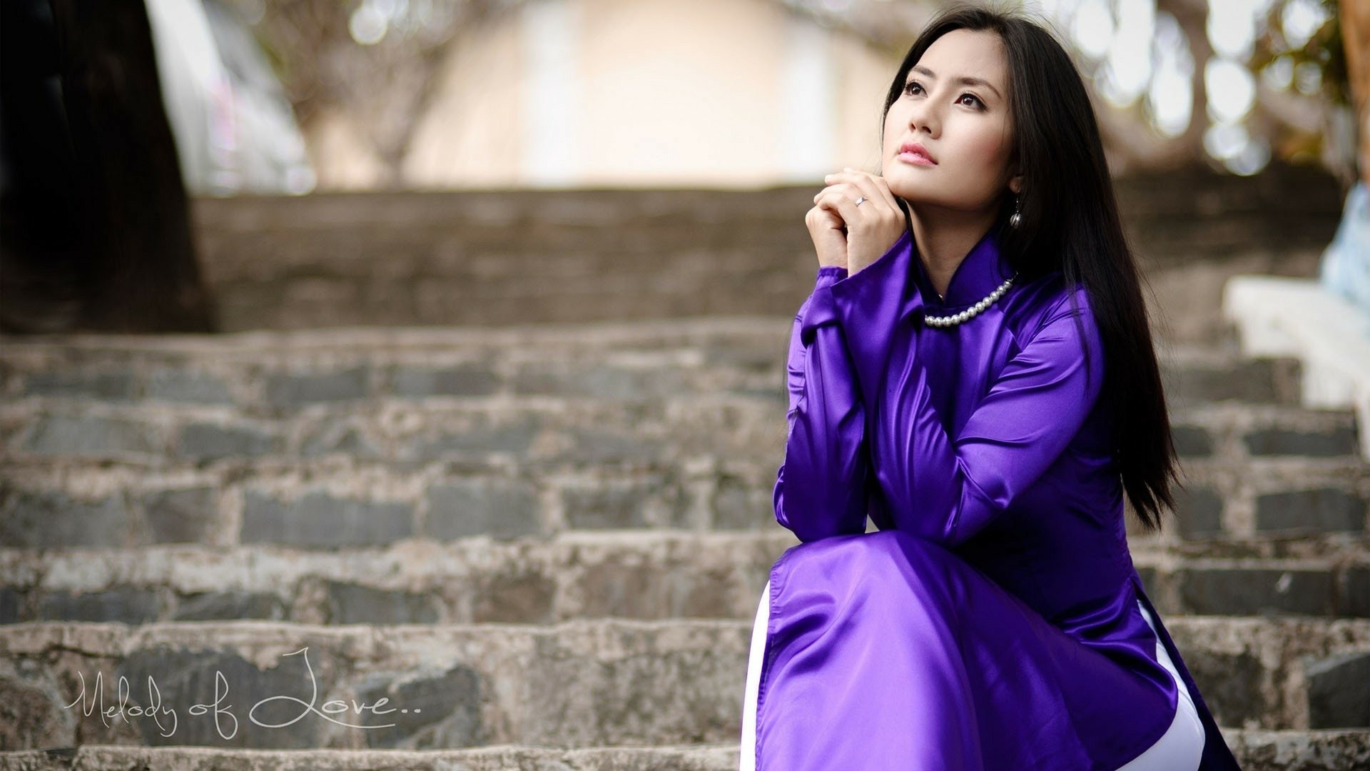 HD desktop wallpaper of an Asian woman in purple traditional attire, sitting on stone steps and looking thoughtfully into the distance.