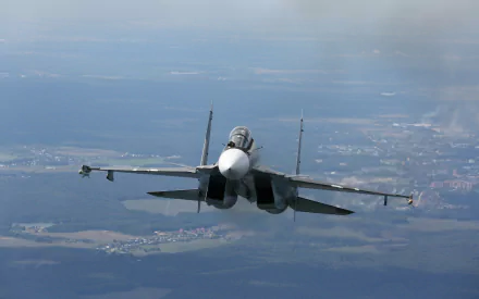 HD desktop wallpaper of a Sukhoi Su-30 warplane in mid-flight over a vast landscape with scattered clouds in the distance. Military aircraft showcasing the sleek design and power of the Sukhoi Su-30.