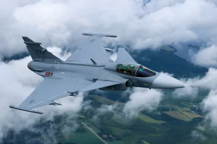 A Saab JAS 39 Gripen jet fighter soars through a cloudy sky, showcasing its sleek design and advanced military capabilities. An impressive HD PC desktop wallpaper featuring military aviation.