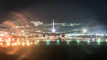A Boeing 777 is illuminated at night, preparing for takeoff with city lights twinkling in the background. This HD wallpaper captures the essence of air travel.