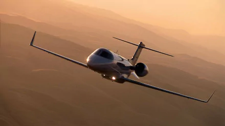 A Learjet aircraft in flight against a warm, mountainous background, captured as an HD PC desktop wallpaper and background.