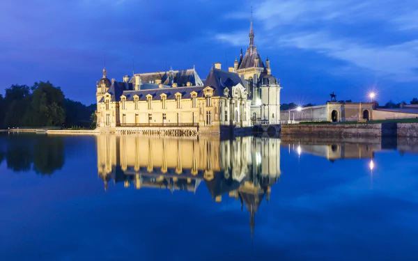 Château de Chantilly in France illuminated at dusk, its detailed architecture beautifully reflected on the calm water, captured in stunning 4K Ultra HD quality.