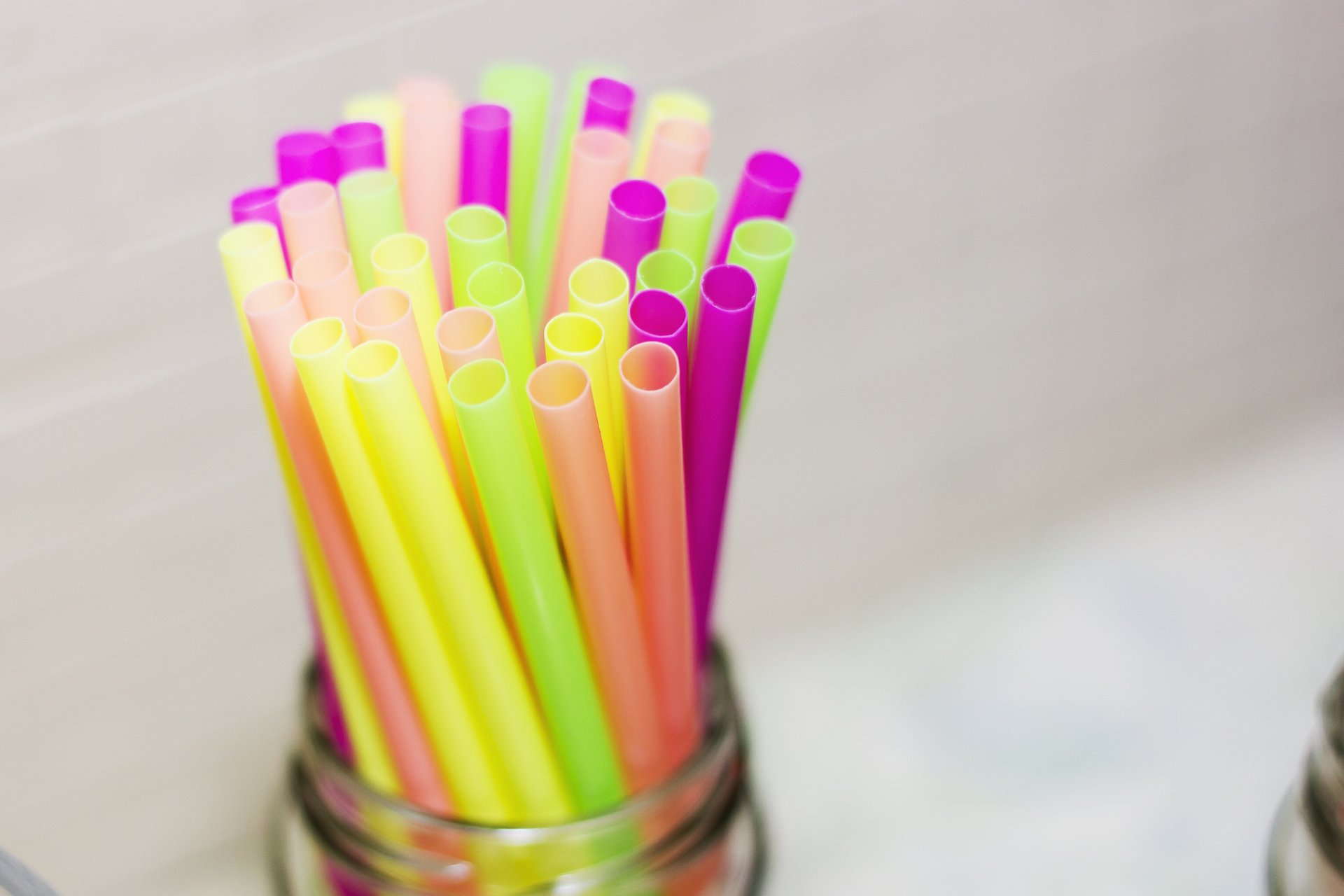 Close-up HD desktop wallpaper of colorful plastic straws arranged upright in a glass jar, showcasing vibrant hues and smooth textures.