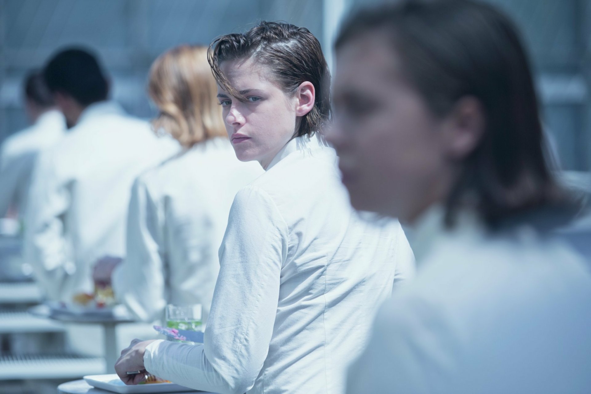 HD desktop wallpaper featuring Kristen Stewart in a scene from the movie Equals, set in a sterile, futuristic environment with characters dressed in white.