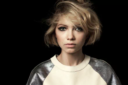 HD desktop wallpaper: close-up of an American blonde actress — young woman with short tousled hair, smoky eye makeup and a neutral expression against a dark background.