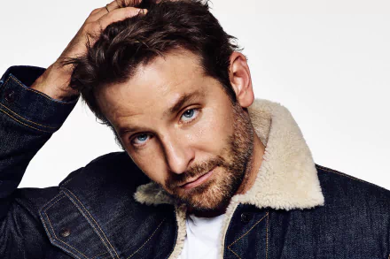 Close-up portrait of a bearded man with striking blue eyes wearing a denim jacket with shearling collar, HD desktop wallpaper background.