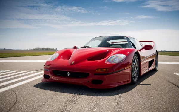 A red Ferrari F50 supercar parked on an open road under a partly cloudy sky, captured in stunning 4K Ultra HD quality.