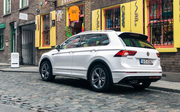 White Volkswagen Tiguan SUV parked on a cobblestone street in an urban setting, captured in 4K Ultra HD for a PC desktop wallpaper.