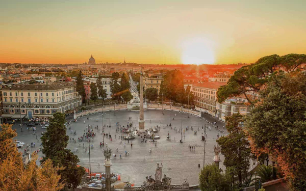 Sunset over Rome’s cityscape featuring an obelisk at the center of a bustling square, with historic buildings and trees framing the vibrant urban scene.