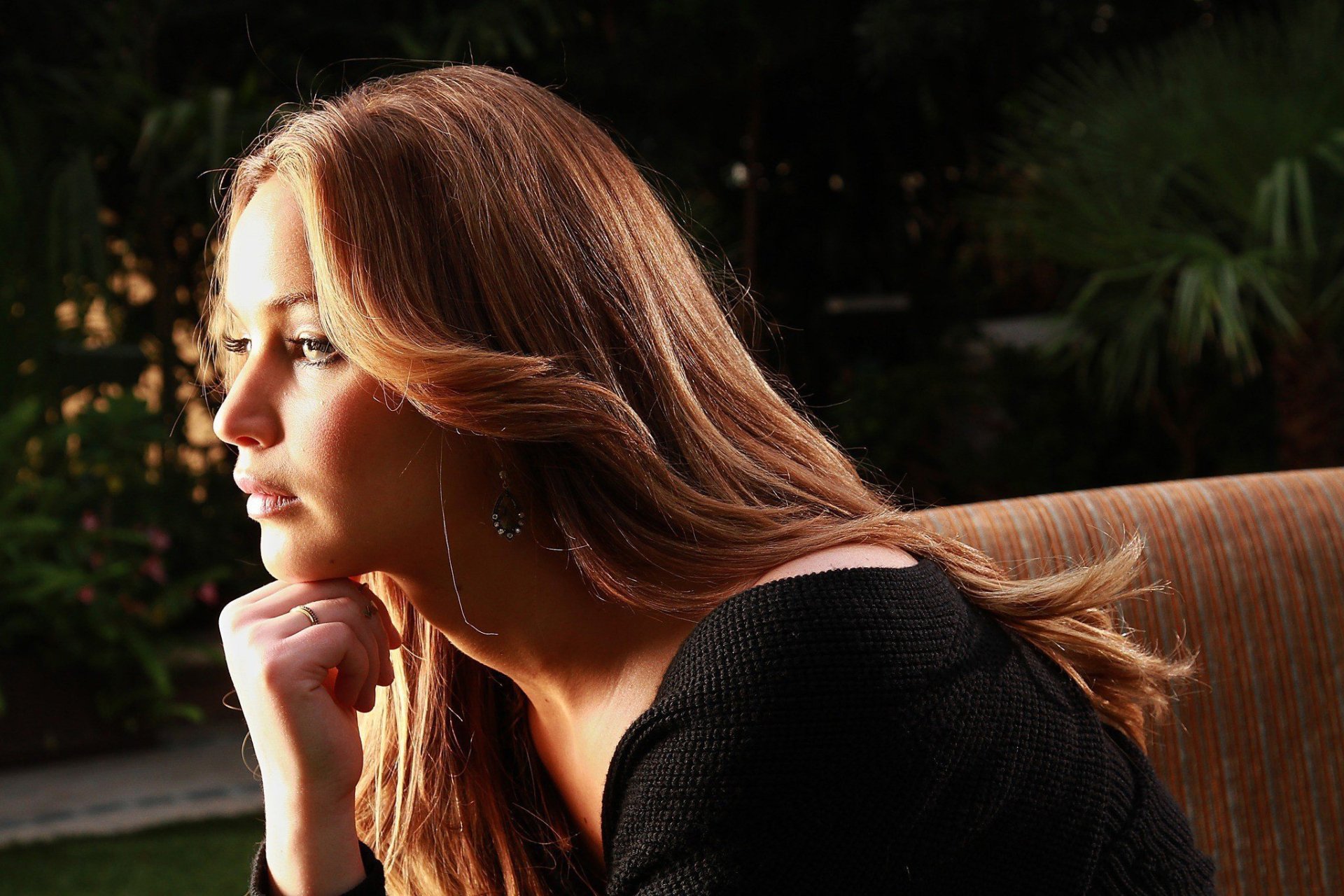 HD desktop wallpaper featuring a close-up side profile of celebrity Jennifer Lawrence against a dark, softly blurred outdoor background.