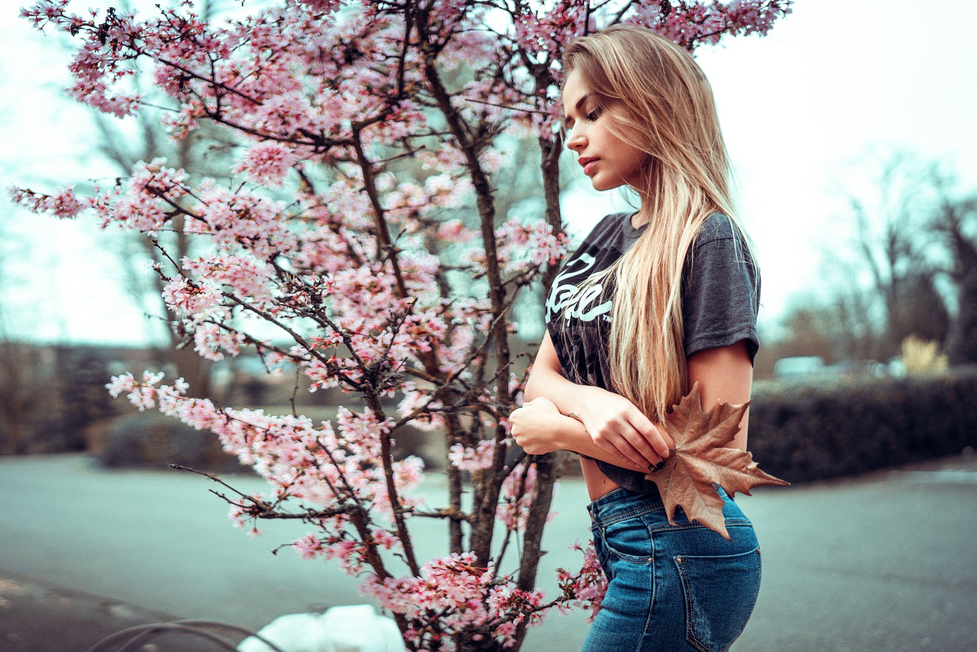 A brunette woman stands outdoors beside a blossoming tree, captured in a serene mood for an HD PC desktop wallpaper and background.