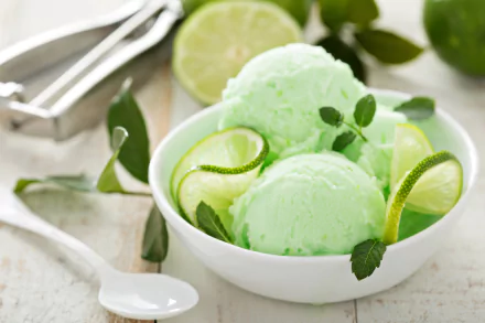 A bowl of mint lime ice cream garnished with lime slices and mint leaves, set against a light background, showcased in vibrant 4K Ultra HD.