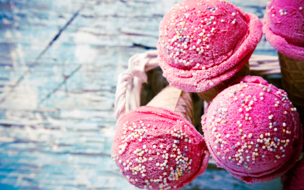 Close-up of vibrant pink ice cream scoops with colorful sprinkles in cones, captured in stunning detail for a 4K Ultra HD PC desktop wallpaper and background.