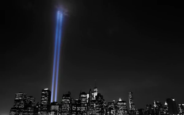 Selective color image of New York City skyline at night with two bright light beams shining upward from skyscrapers, highlighting the man-made urban landscape.