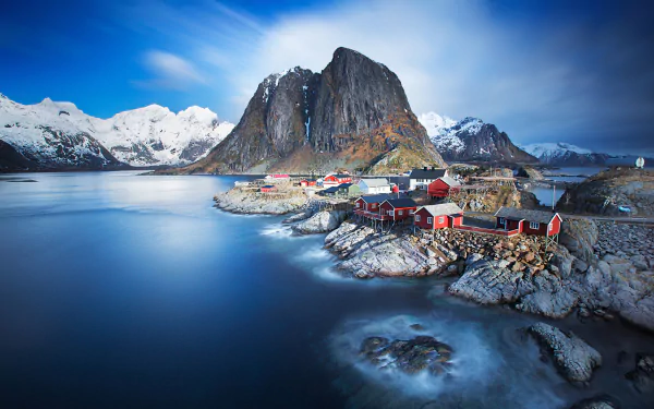 A stunning landscape of Reine in Lofoten, featuring a tranquil lake, dramatic mountains, and a charming village with red houses, captured in high-definition for an impressive desktop background.
