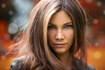 A close-up of a model with brunette hair, freckles, and striking green eyes, set against a softly blurred background, creating an engaging HD desktop wallpaper.