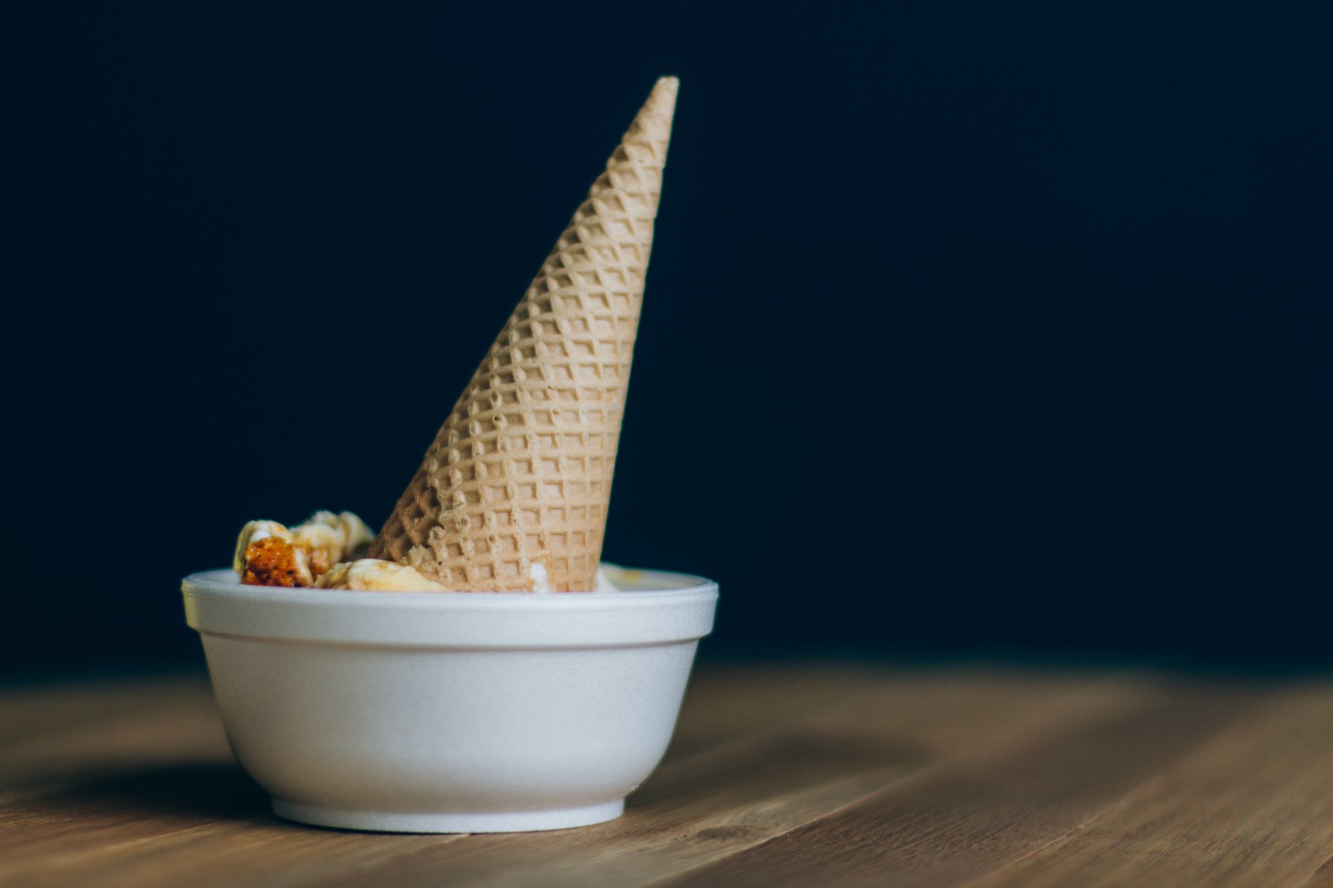 A 4K Ultra HD desktop wallpaper featuring an upside-down waffle cone in a white bowl on a wooden surface against a dark background, highlighting food and ice cream themes.