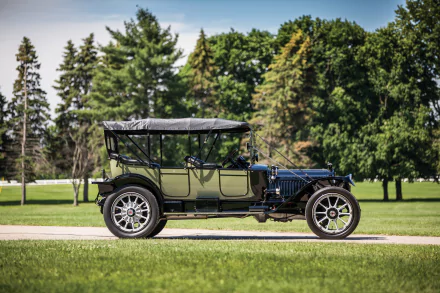 Vintage 1914 Packard Six 5-passenger Touring car parked on a grassy path with lush green trees in the background, captured in high definition for PC desktop wallpaper.