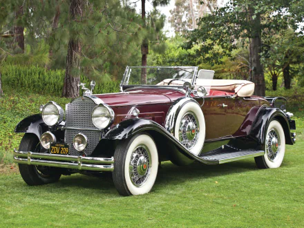 A vintage 1931 Packard Deluxe Eight Roadster in deep burgundy, showcased outdoors on green grass, captured as an HD PC desktop wallpaper and background.