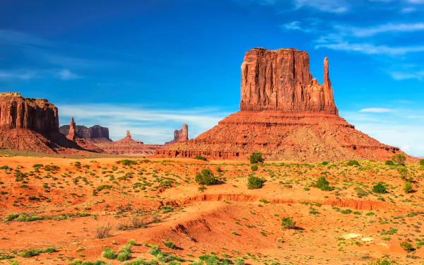 Vibrant desert landscape in Monument Valley, Arizona, showcasing stunning red rock formations under a clear blue sky. A breathtaking nature scene for any desktop wallpaper.