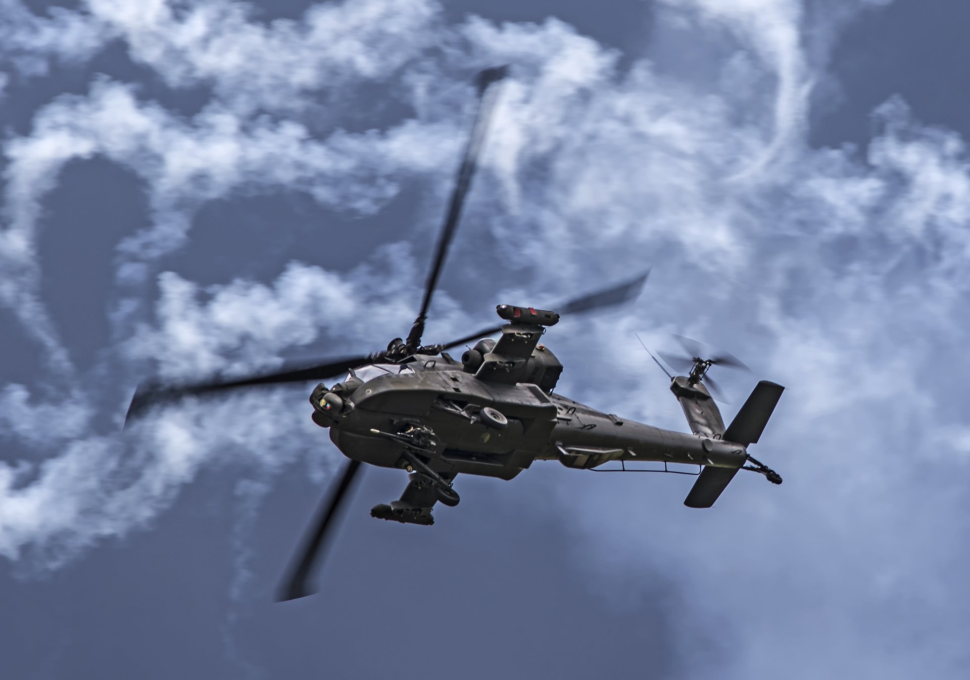A Boeing AH-64 Apache attack helicopter flies against a cloudy sky, captured in 4K Ultra HD detail for a PC desktop wallpaper.