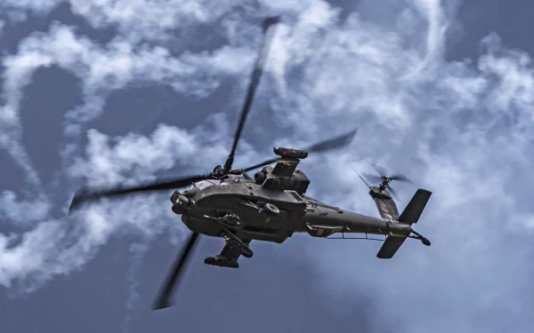 A Boeing AH-64 Apache attack helicopter flies against a cloudy sky, captured in 4K Ultra HD detail for a PC desktop wallpaper.