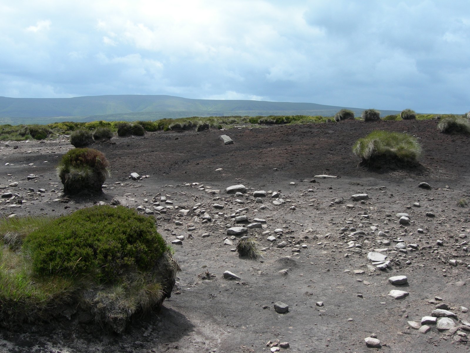 HD PC desktop wallpaper showcasing a rugged natural landscape with scattered green mossy rocks under a cloudy sky.