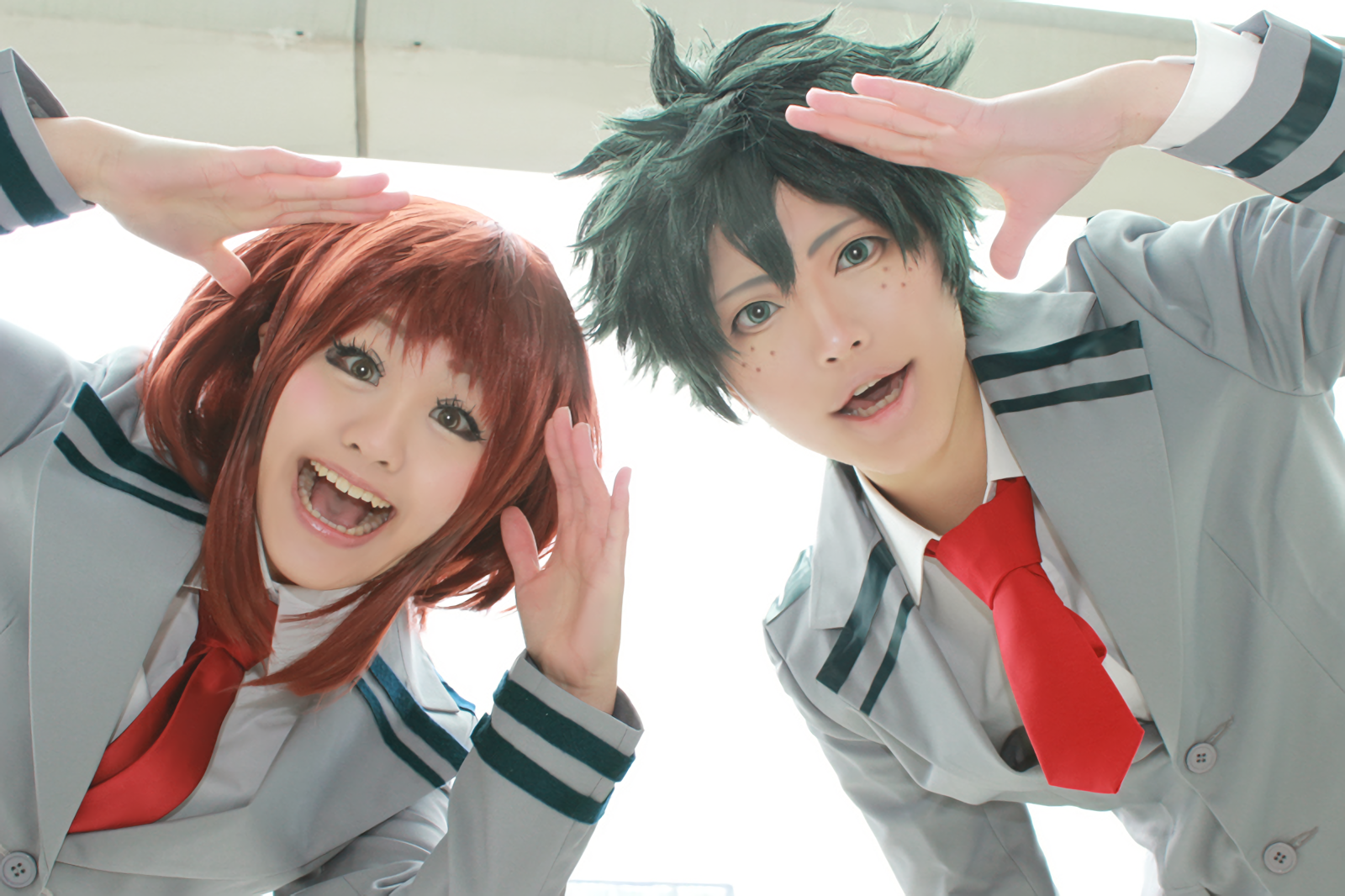 HD PC desktop wallpaper featuring women cosplaying as Ochaco Uraraka and Izuku Midoriya from My Hero Academia, dressed in school uniforms with cheerful expressions.