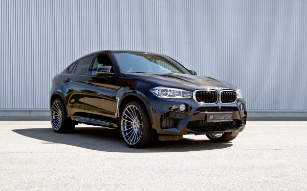 HD desktop wallpaper featuring a sleek black BMW X6 SUV parked on a concrete surface against a modern industrial backdrop.