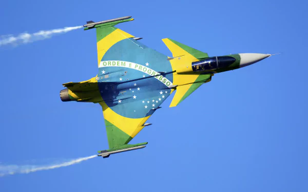 A Saab JAS 39 Gripen jet fighter adorned with the Brazilian flag flies through a clear blue sky, showcasing its military prowess and vibrant colors in a striking HD wallpaper.