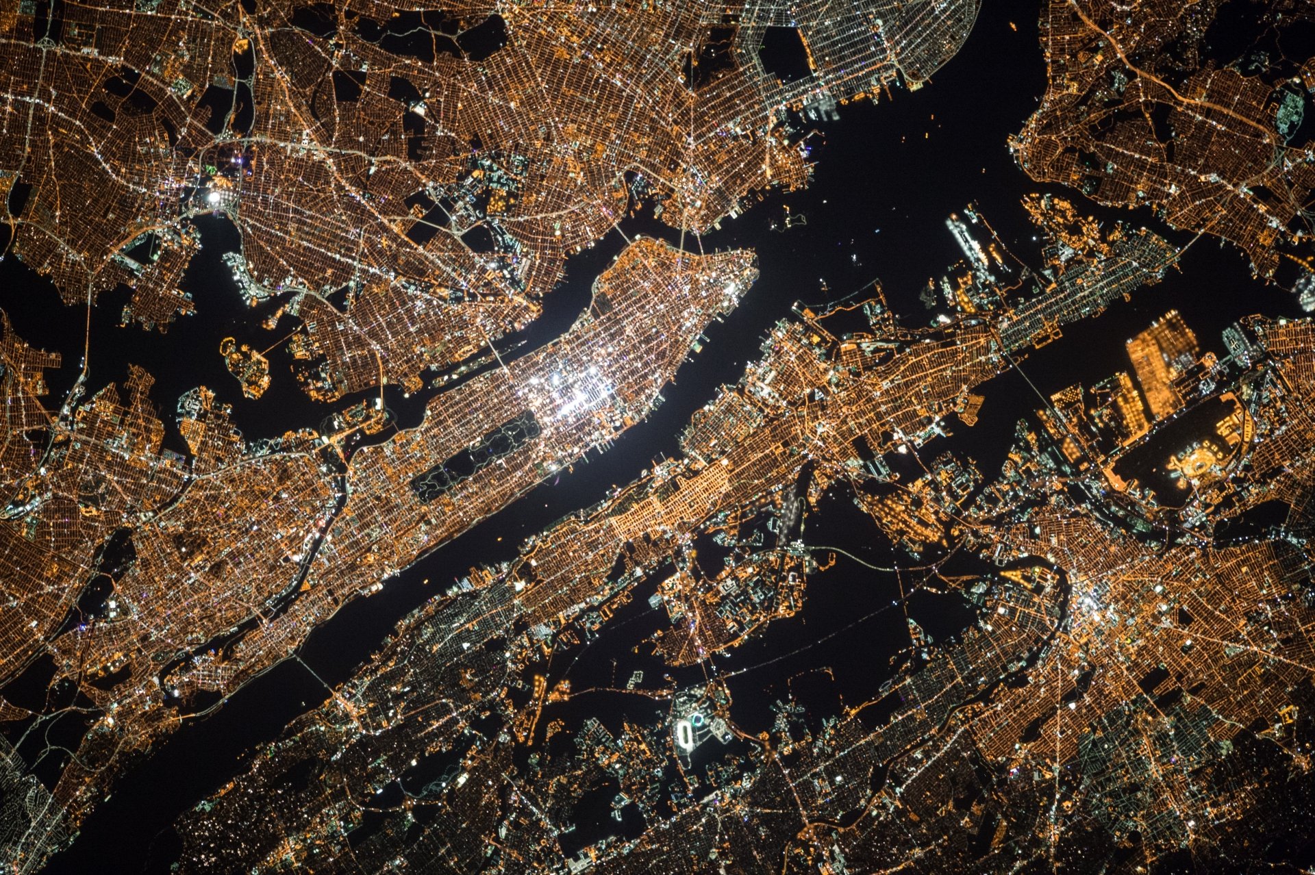 Aerial 4K Ultra HD night cityscape of New York and New Jersey, showcasing brightly lit urban streets and waterways in the USA.