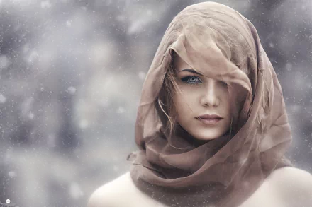 HD desktop wallpaper featuring a woman with a serene expression, partially veiled by a translucent scarf. Snowflakes fall around her, adding a wintry feel.