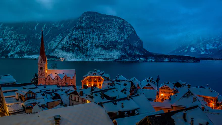 Snow-covered Hallstatt village illuminated at night against a mountainous winter backdrop, captured in 4K Ultra HD as a stunning PC desktop wallpaper.