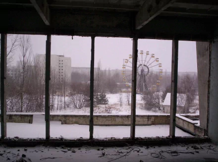 A haunting view of the abandoned Pripyat Amusement Park in winter, showcasing the dilapidated ferris wheel amidst a snowy landscape, reflecting the eerie remnants of Chernobyl.