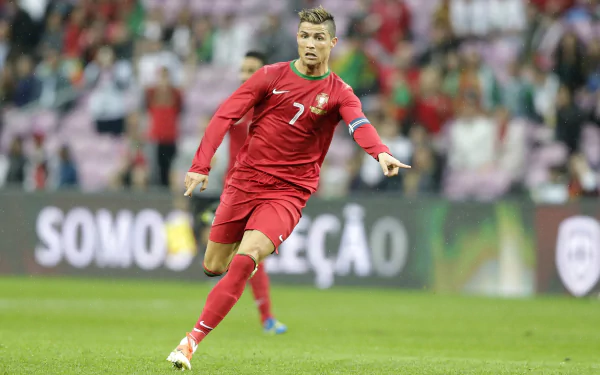 Cristiano Ronaldo in action during a soccer match, wearing Portugal's national team uniform. The HD desktop wallpaper captures the dynamic energy of the sports scene.