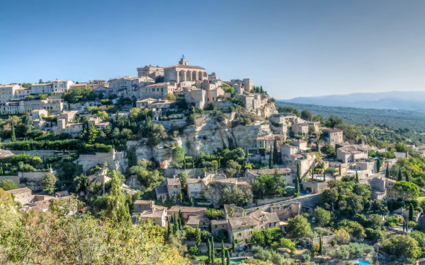 Scenic HD desktop wallpaper of a charming Provence hilltop town in France, showcasing historic houses and lush green landscape under a clear blue sky.
