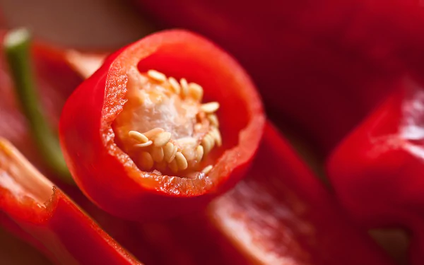 5K Ultra HD PC desktop wallpaper: close-up of a vibrant red pepper sliced to reveal seeds and glossy flesh, food-themed background.