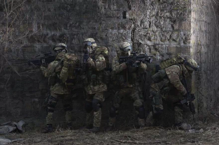 HD wallpaper featuring four soldiers in military gear, armed with firearms, taking cover against a weathered stone wall.