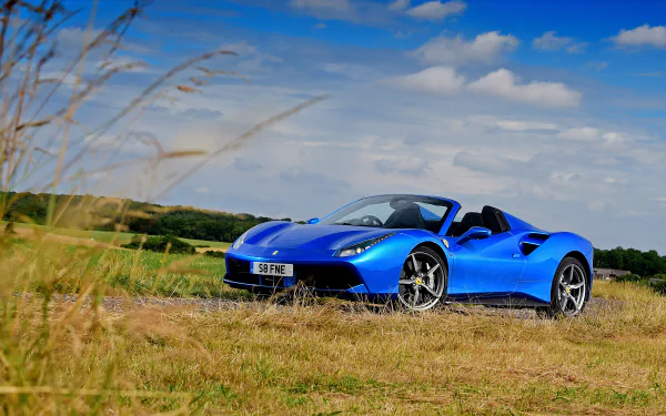 HD PC desktop wallpaper featuring a vibrant blue Ferrari 488 Spider parked on a grassy field under a partly cloudy sky.